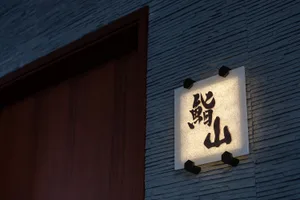 A modern restaurant signage with paper lightbox illumination displaying black characters against a wooden background.