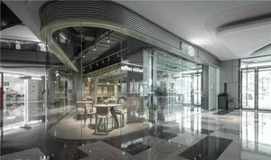 Modern minimalist coffee shop interior with glass walls, sleek tables, and white chairs.