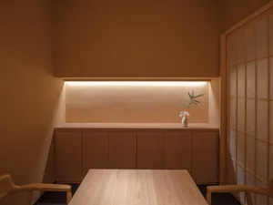 Minimalist design with a small space, wooden table, and ceramic vase with flowers.