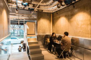 People enjoying a conversation in a modern cafe with concrete walls and minimalist design