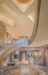 A modern lobby featuring marble walls and floors with a sculptural central piece and a large spherical ornament.
