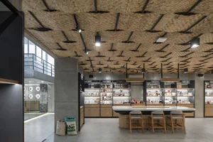 Interior design of a coffee shop featuring a bamboo ceiling and concrete columns with a display of coffee-related products an