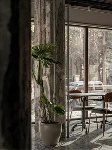 A minimalist cafe interior featuring exposed concrete columns and seating.