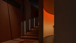 A minimalist hallway with concrete walls and stairs leading to a curved opening.