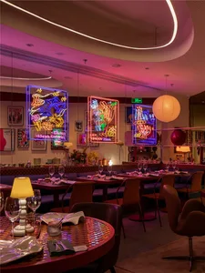 A restaurant interior with industrial design, featuring metal neon signs and vintage lighting fixtures.