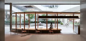 Modern cafe interior featuring glass walls, wooden seating, and concrete floor.