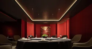 A luxurious private dining room with red leather seating and a circular dining table.