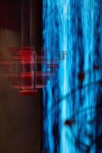 Minimalist art installation featuring metallic rods on a blue background.