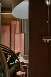 Modern restaurant interior featuring glass folding doors with a wooden table and red plates.