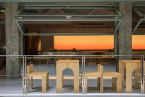 Attractive modern restaurant interior with a focus on wooden furniture and a sunset view.