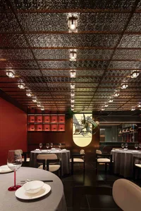 A modern restaurant interior with metallic ceiling, round tables, and chairs.