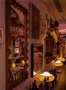 A cozy, wooden-themed restaurant bar with glass bottles and framed posters.