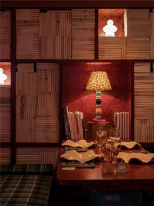 A modern restaurant setting with wooden shelves, a table setup, and a decorative lamp.