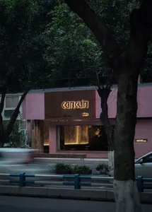 A pink-painted storefront at night, featuring a glowing sign with the name 'Cancún'.