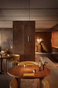 A modern industrial restaurant interior with metallic finishes, rounded tables, and minimalist decor.
