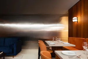 Modern restaurant interior featuring metallic wall panels and wooden paneling.