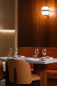 A modern restaurant interior featuring wooden walls, leather seating, and glassware.