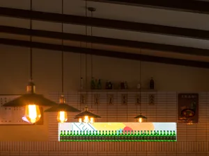 A brick-tiled bar counter with green bottles arranged in a row on the shelf.