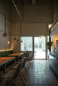 A modern cafe interior featuring wooden tables, metal chairs, and glass elements.