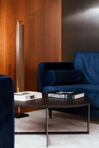Modern living room featuring a blue velvet couch and a wooden panel wall.