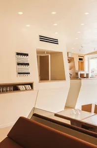 Modern minimalist cafe interior with white walls, defense wood accents, and a clean, open layout.