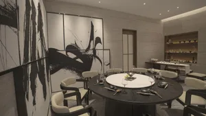 Modern dining room with black and white decor, featuring a round table, chairs, and abstract wall art.