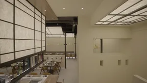 A modern restaurant interior with minimalist design, showcasing sleek white walls and lighting.