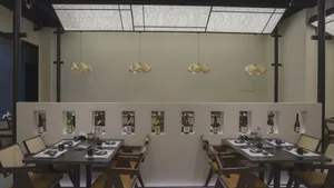 Minimalist design featuring wooden tables, concrete walls, and glass windows in a modern restaurant setting.