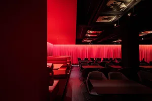 A modern restaurant with red curtains and tables.