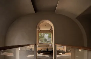 A modern living room with concrete arches, featuring a comfortable sofa and a coffee table, set against a backdrop of natural