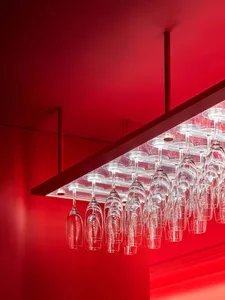 A modern minimalist bar counter with clear glass hanging shelves.