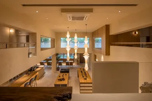 Modern, minimalist cafe interior featuring wooden furniture, natural lighting, and minimalist decor.