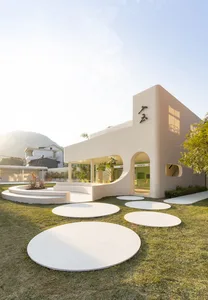 A minimalist house exterior made of concrete and plaster against a clear blue sky.