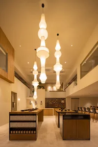 Modern coffee shop interior with wooden furniture, glass walls, and hanging paper lanterns.