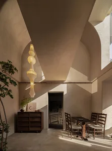 A modern residential interior with natural light, wooden furnishings, and concrete finishes.