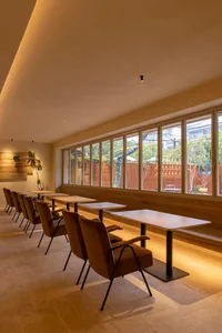 Modern restaurant interior with tables, chairs, and large windows.