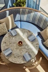 A photograph of a blue-themed dining room featuring marble table and upholstery, with place settings, chairs, and decorative