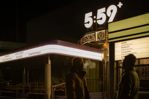 A modern entrance to an API restaurant, featuring a concrete facade and illuminated signage.