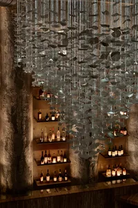 A modern bar interior featuring a metallic hanging installation