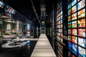A modern, illuminated corridor with colorful glass wall panels and black flooring.