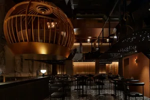 A modern restaurant interior featuring metallic structures and leather seating.