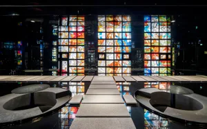 A spacious church interior with concrete flooring and vibrant stained-glass windows.