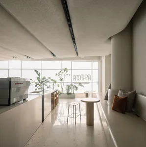 A modern coffee shop with a terrazzo floor and concrete walls.