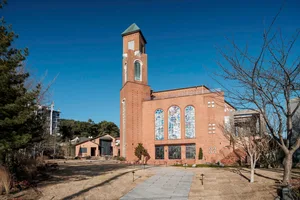 Modern, minimalist brick church with stained glass windows and a tall tower.