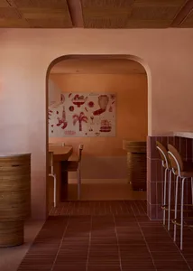 Clay-tiled restaurant bar with wooden stools and a mural on the wall.
