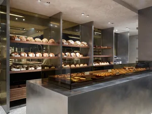 Modern bakery shop interior featuring glass display cases and metal shelving.