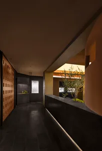 Modern interior corridor with concrete walls and floors, illuminated by warm lighting.