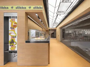 Modern food court with concrete counter displaying pastries and desserts.