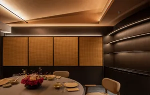 Modern restaurant interior design featuring wooden paneling, round table with plates, glasses, and floral centerpiece.
