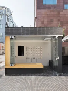 A modern exhibition space featuring a glass display case and various objects on a wooden platform.